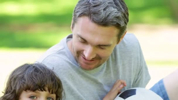 Pai sentado com o pequeno filho segurando futebol — Vídeo de Stock