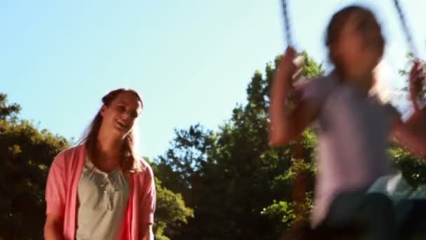 Girl being pushed on a swing by her mother — Stock Video