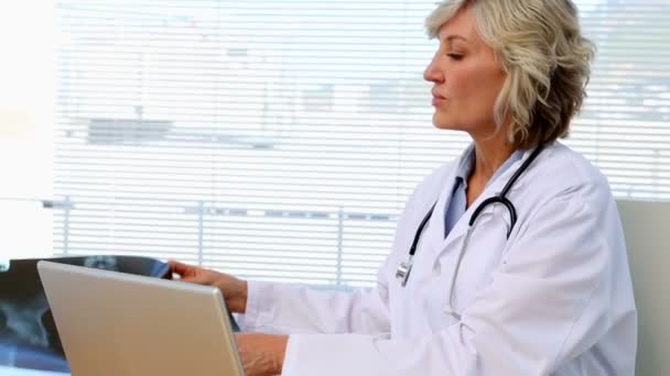 Blonde doctor looking at xray at her desk — Stock Video