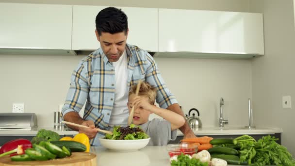 Vater zeigt seinem Sohn, wie man Salat wirft — Stockvideo