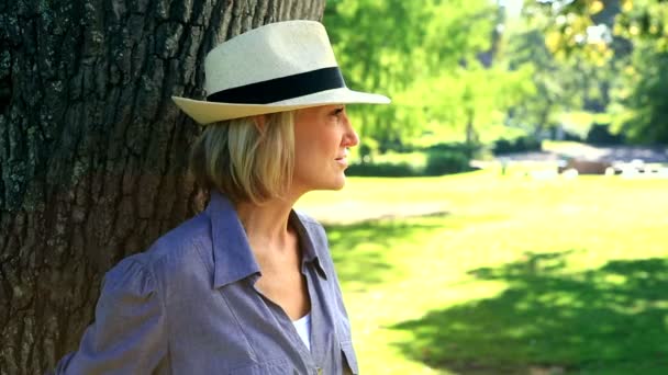 Femme souriante appuyée contre un arbre — Video