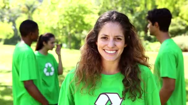 Activista ambiental sonriendo a la cámara con el equipo detrás de ella — Vídeo de stock