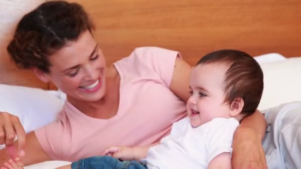 Feliz madre cosquillas bebé hijo en la cama — Vídeos de Stock