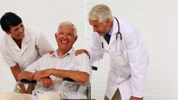 Doctor and nurse talking with elderly patient in a wheelchair — Stock Video