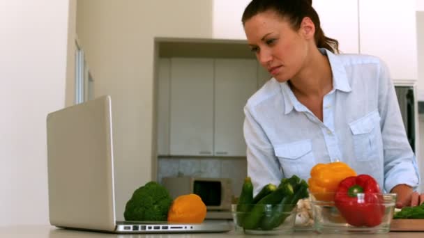 Mujer siguiendo receta en el ordenador portátil — Vídeo de stock