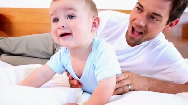 Happy father tickling his baby son on bed — Stock Video