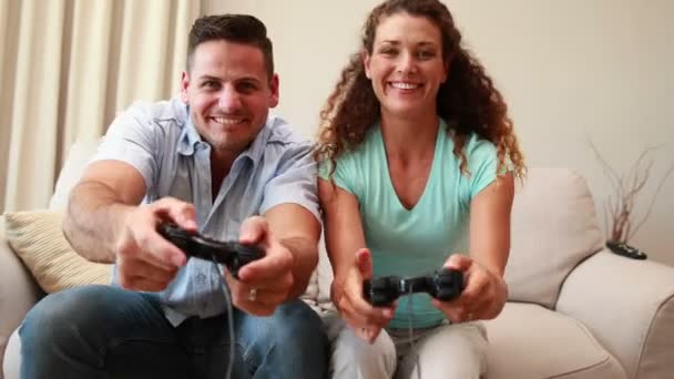 Jeune couple assis sur un canapé jouant à des jeux vidéo — Video