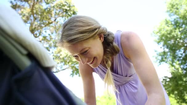 Moeder neiging om haar baby girl in haar pram in het park — Stockvideo