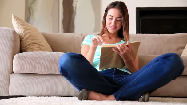 Гарненька брюнетка розслабляється на килимі читання — стокове відео