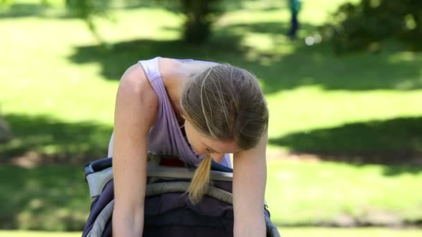 Мать ухаживает за своей малышкой в коляске в парке — стоковое видео