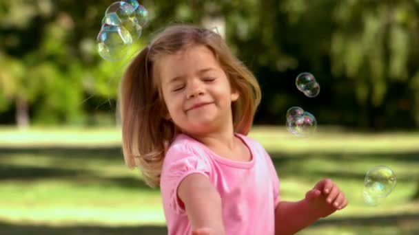 Niña jugando con burbujas en el parque — Vídeos de Stock