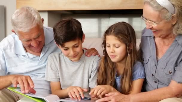 Grootouders chatten met kleinkinderen kijken naar fotoalbum — Stockvideo