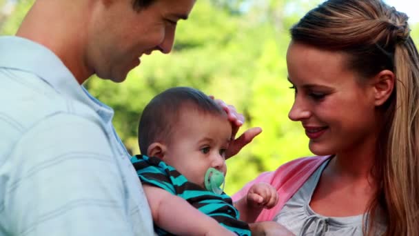 Orgullosos padres sosteniendo al bebé en el parque — Vídeo de stock