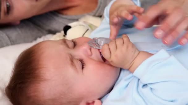 Gelukkige ouders liggend op bed met baby zoon — Stockvideo