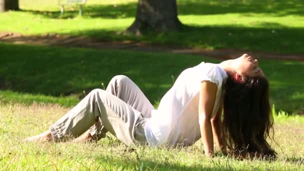 Meisje, zittend op het gras genietend van de zon — Stockvideo