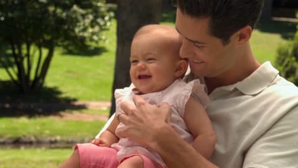 Man holding his baby daughter in the park — Stock Video