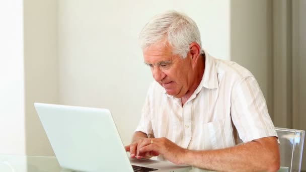 Senior man met laptop aan de tafel — Stockvideo