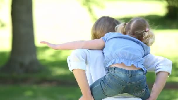 Chica recibiendo un cerdito de vuelta de la madre en el parque — Vídeo de stock