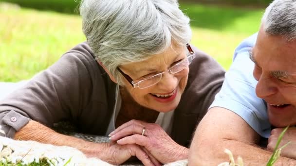 Cariñosa pareja de ancianos relajarse en el parque acostado en la manta — Vídeos de Stock