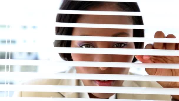 Businesswoman looking through blinds — Stock Video