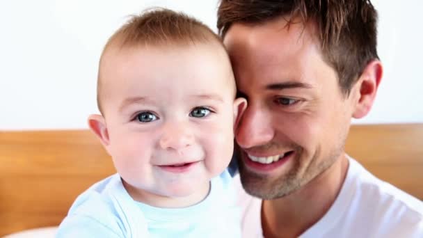 Feliz padre sentado con el bebé hijo en la cama — Vídeo de stock