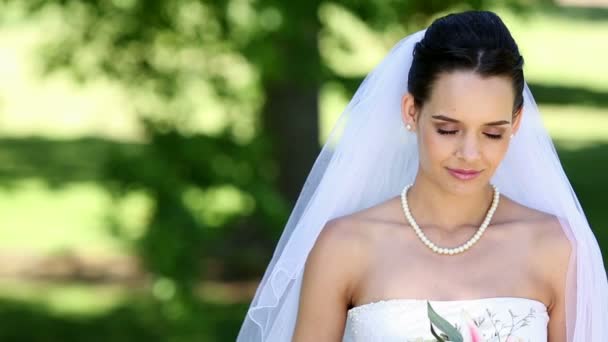 Beautiful bride smiling at camera in the park — Stock Video