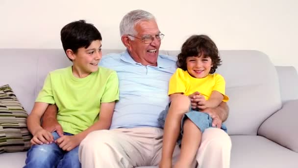 Senior man sitting on couch with his grandsons — Stock Video