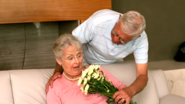 Senior man surpising partner with flowers on the couch — Stock Video