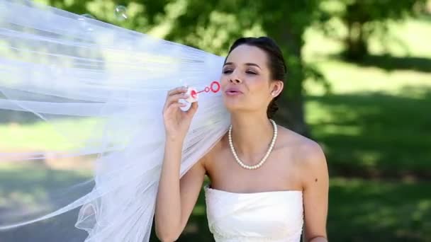 Beautiful bride blowing bubbles in the park — Stock Video