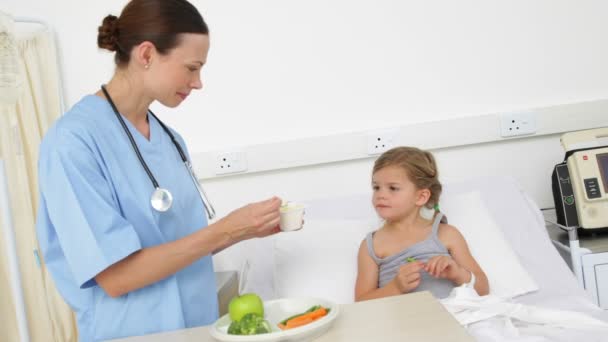 Nurse feeding sick little girl in bed — Stock Video
