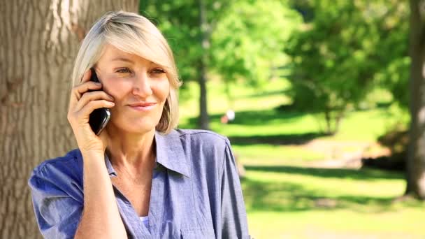 Vrouw chatten op haar telefoon in het park — Stockvideo