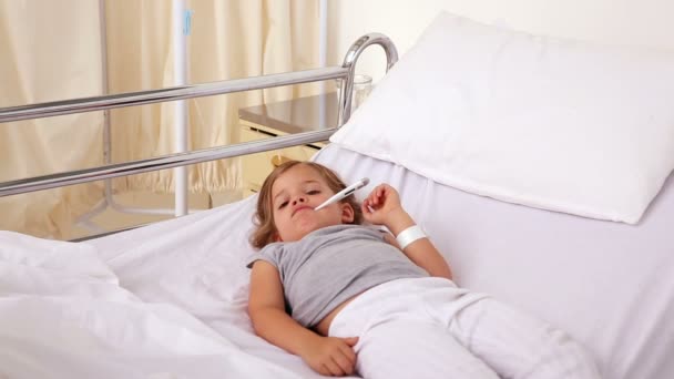 Κοριτσάκι ξαπλωμένη στο κρεβάτι του νοσοκομείο με ένα θερμόμετρο — Αρχείο Βίντεο