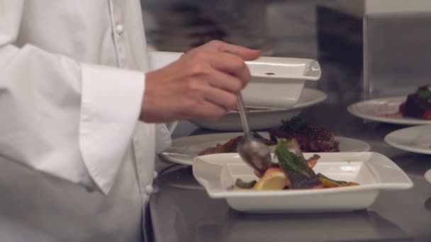 Chef-kok gieten saus over vis schotel — Stockvideo