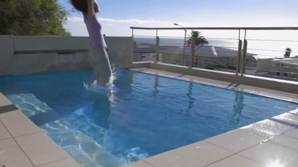 Frau springt voll bekleidet in Pool — Stockvideo