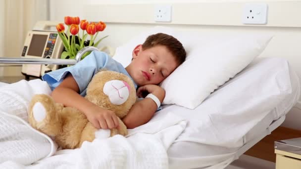 Little sick boy sleeping in bed with teddy bear — Stock Video