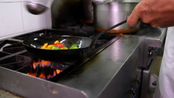 Шеф-повар жарит овощи в воке и добавляет ковш с водой — стоковое видео