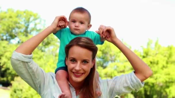 Moeder bedrijf schattige baby zoon op haar schouders — Stockvideo