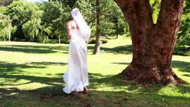 Sposa eccitata che tiene un bouquet nel parco — Video Stock