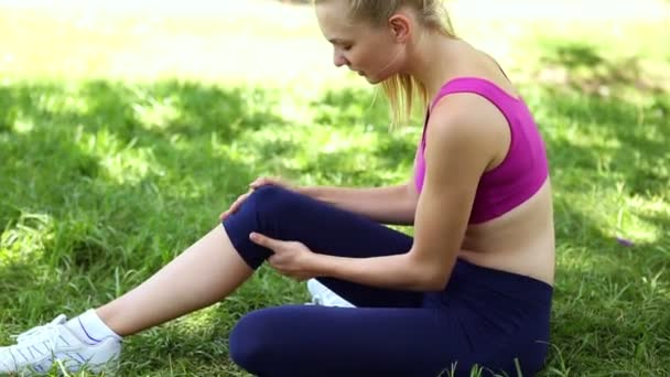 Blessé ajustement blonde toucher son genou sur l'herbe — Video