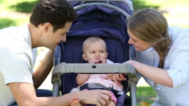 Parents tending to baby girl in pram — Stock Video