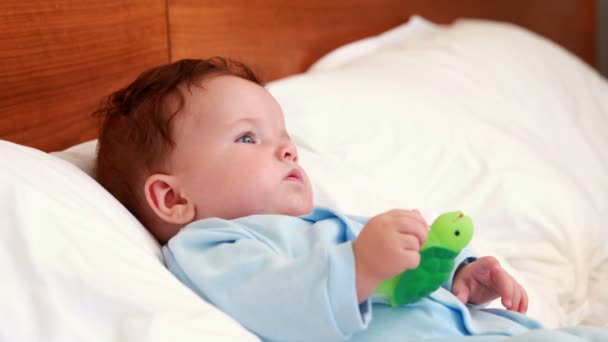 Babyjongen in babygro liggend op bed — Stockvideo