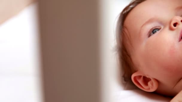 Baby i blöja spelar med mobil i sin spjälsäng — Stockvideo