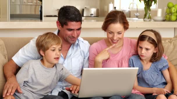 Familia feliz sentado en el sofá utilizando el ordenador portátil — Vídeos de Stock