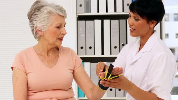 Nurse showing elderly patient how to put on wrist brace — Stock Video