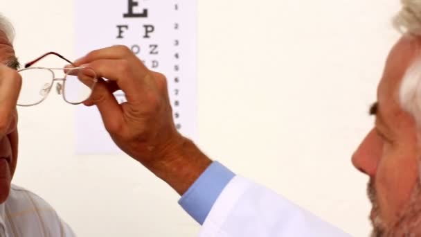 Doctor fitting glasses onto an elderly patient — Stock Video