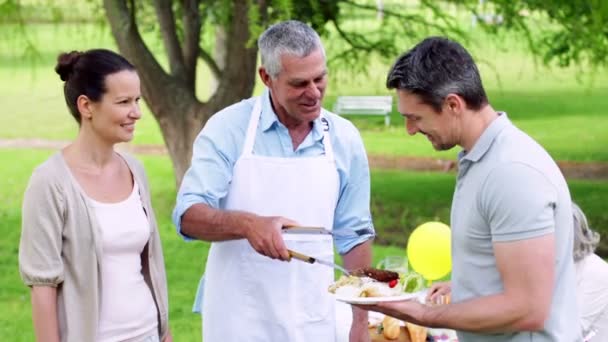 Grandfather serving burgers at family barbecue — Stock Video