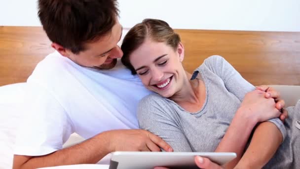 Šťastný pár, ležící na posteli společně pomocí tabletu — Stock video