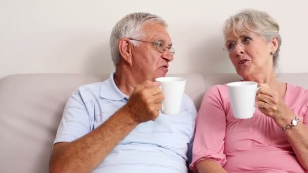 Feliz pareja de ancianos tomando café en el sofá — Vídeo de stock