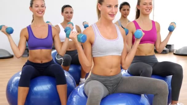 Clase de fitness sentada sobre bolas de ejercicio levantando pesas de mano — Vídeos de Stock