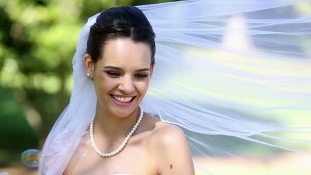 Beautiful bride smiling at camera in the park — Stock Video